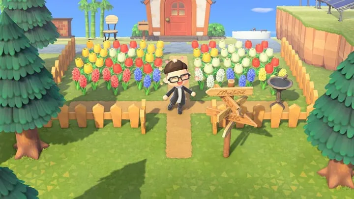 Official Animal Crossing New Horizons screenshot of a landscaped garden with flowers, fences, trees, and outdoor furniture
